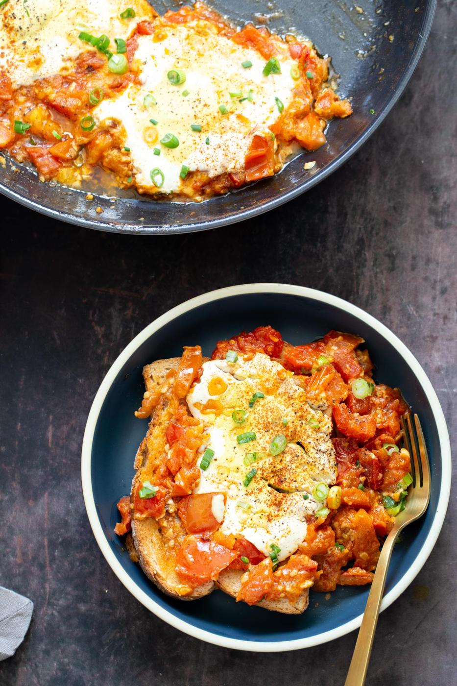 a serving of vegan tofu eggs in purgatory in a blue bowl with a golden fork on the side