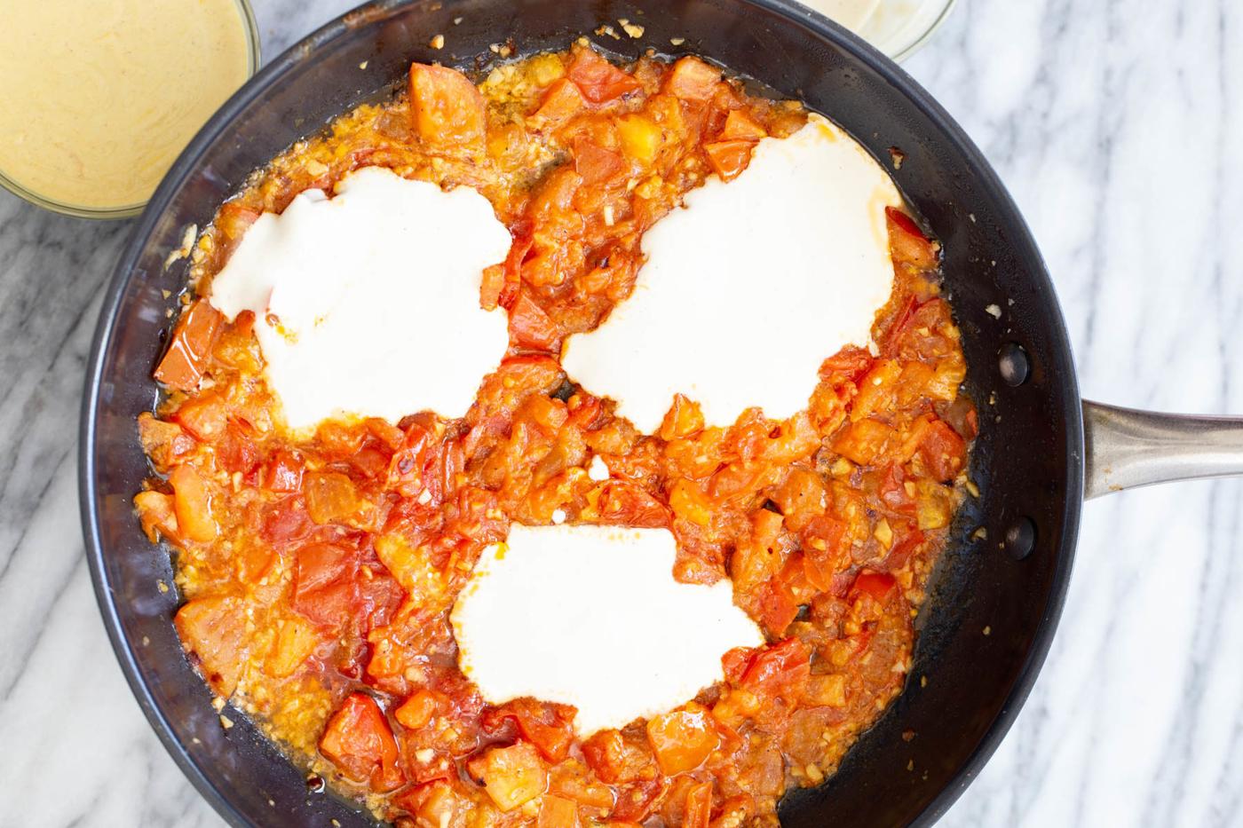 tofu mix being added to pan with tomato sauce to make vegan eggs in purgatory