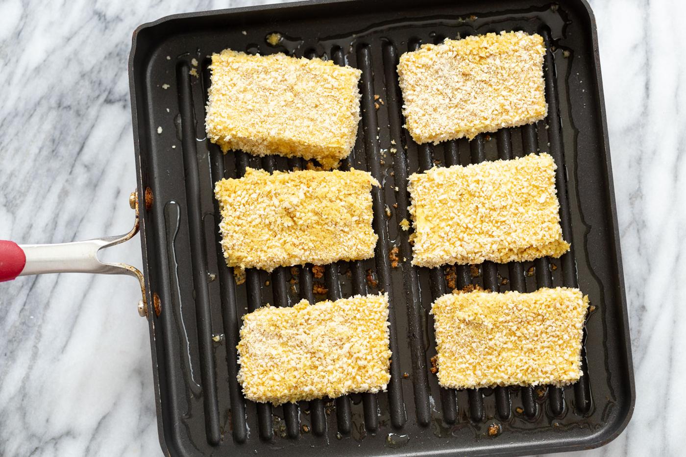 breaded tofu slices being fried in a pan