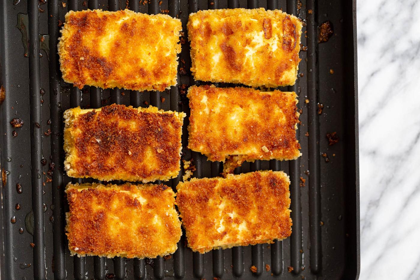 breaded tofu sliced being fried in a grilling pan