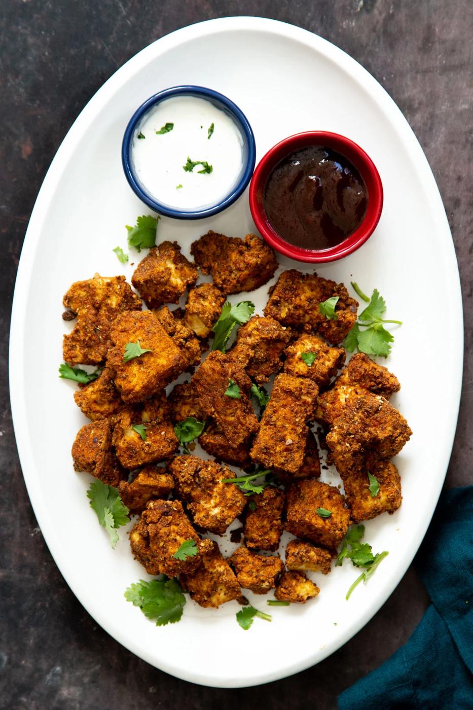 vegan baked tofu nuggets on a white plate with two different dips