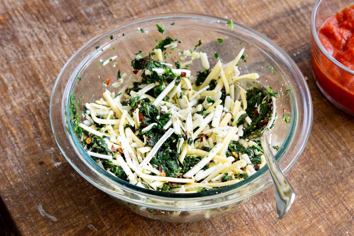 grated vegan cheese, spinach and seasonings in a glass bowl