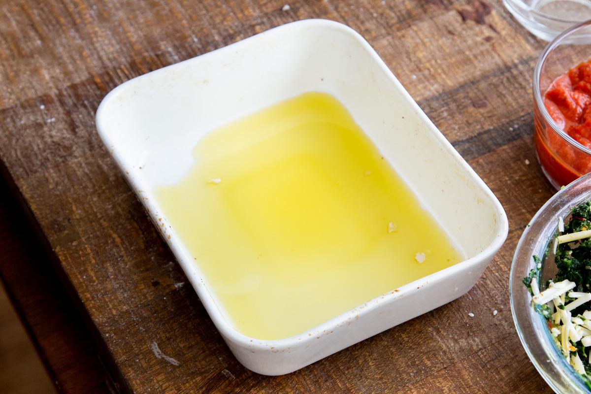 olive oil being spread in a small casserole dish