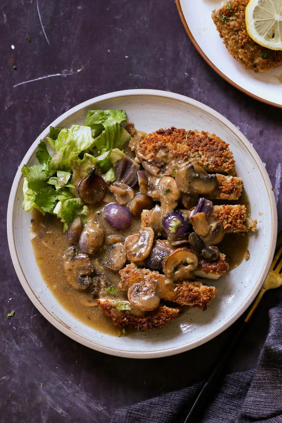 tofu schnitzel on a plate with salad and mushroom gravy