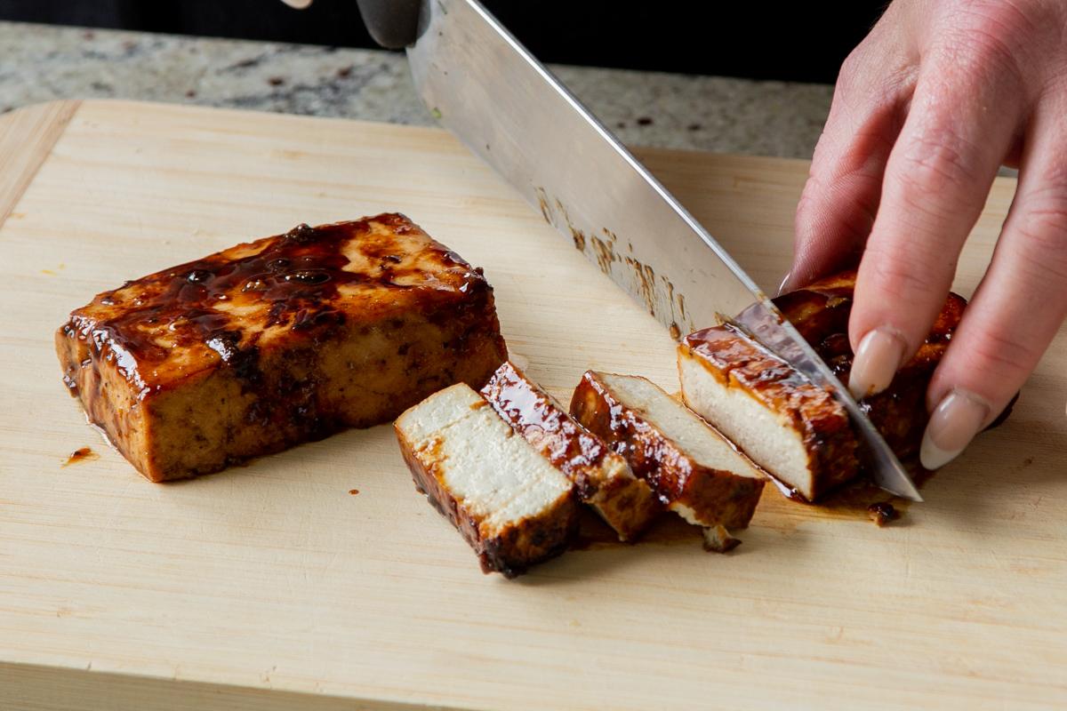 slicing the seared tofu into pieces