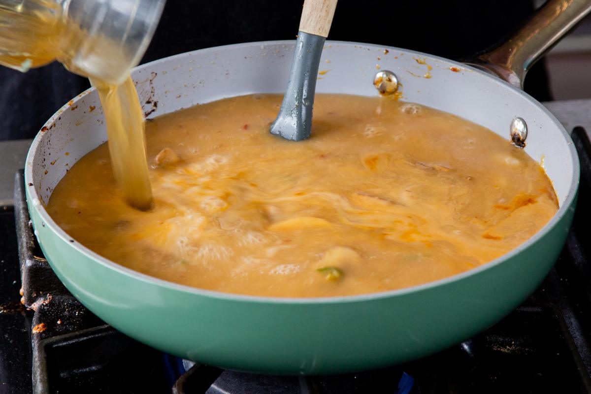 adding broth to the ramen stock