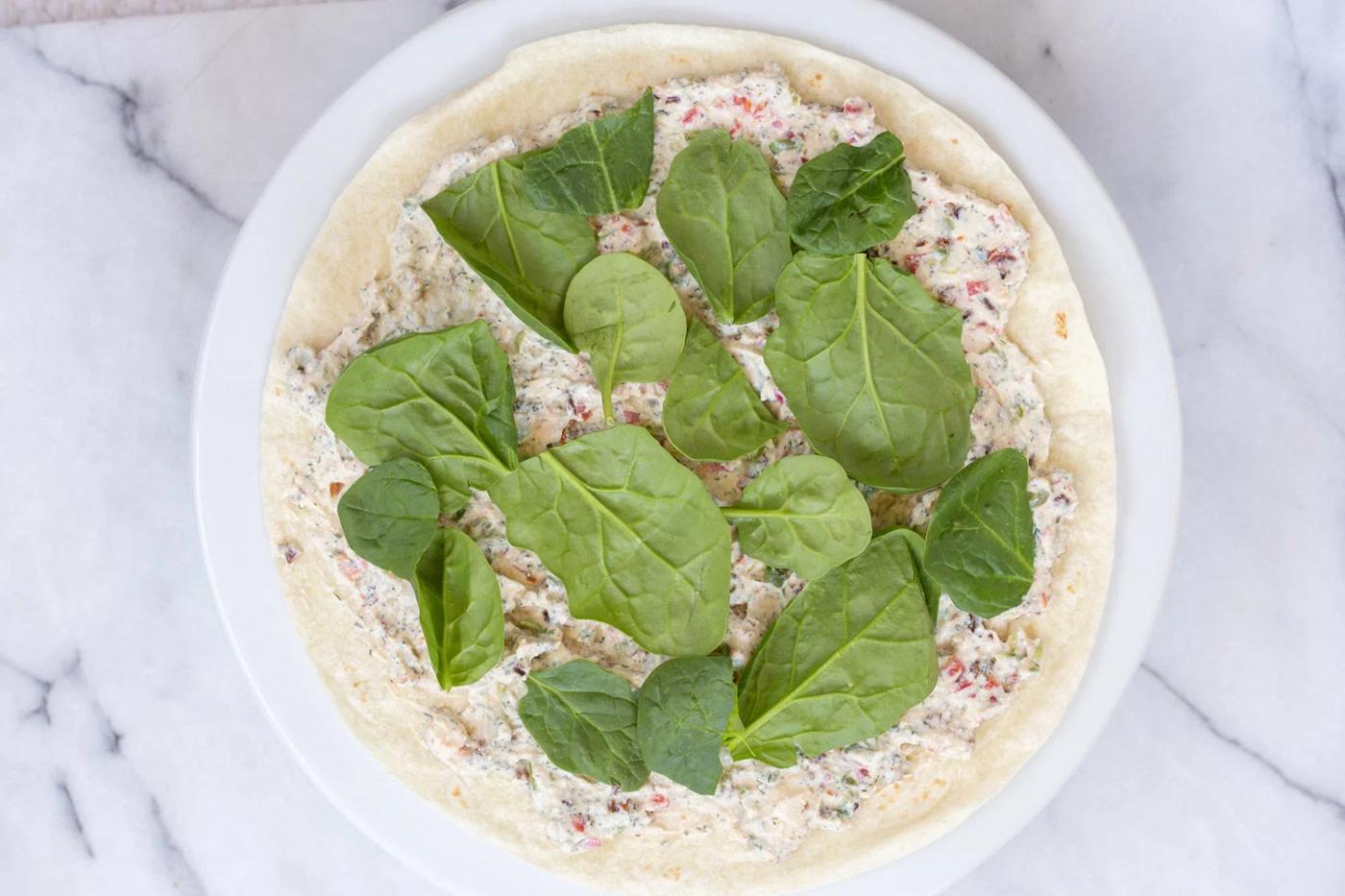 Dairy free Veggie Cream Cheese and Spinach spread on tortilla for our Vegan Tortilla Roll ups recipe