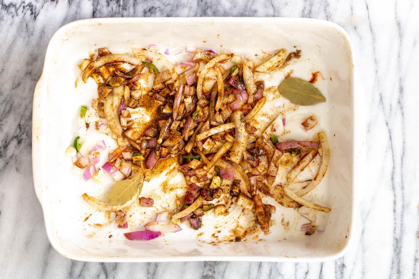 onion, garlic and spices baking in a white casserole dish