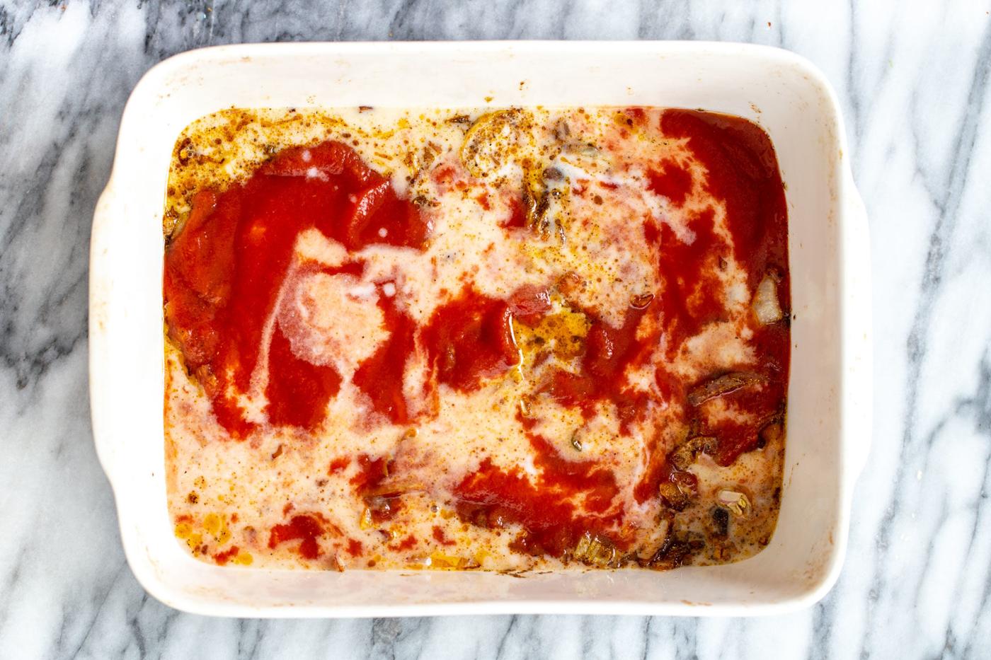 tomato sauce and coconut milk being added to casserole dish to make vegetable casserole