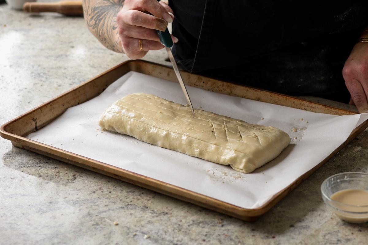 slicing decorative vents into the puff pastry with scissors