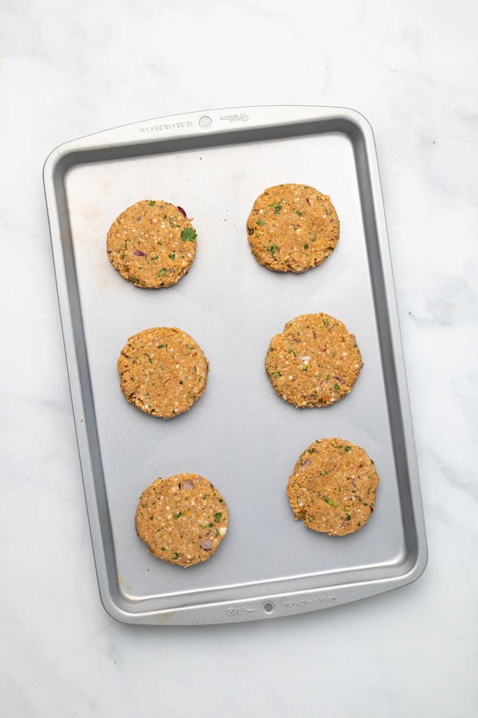 overhead shot of vegan chickpea burger patties lined up on a cookie sheet