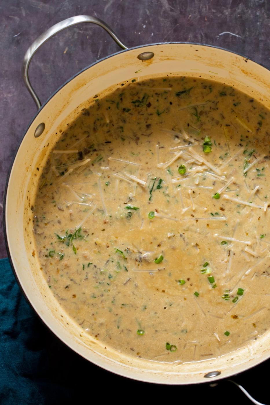 a pot with creamy vegan zuppa toscana topped with shredded cheese