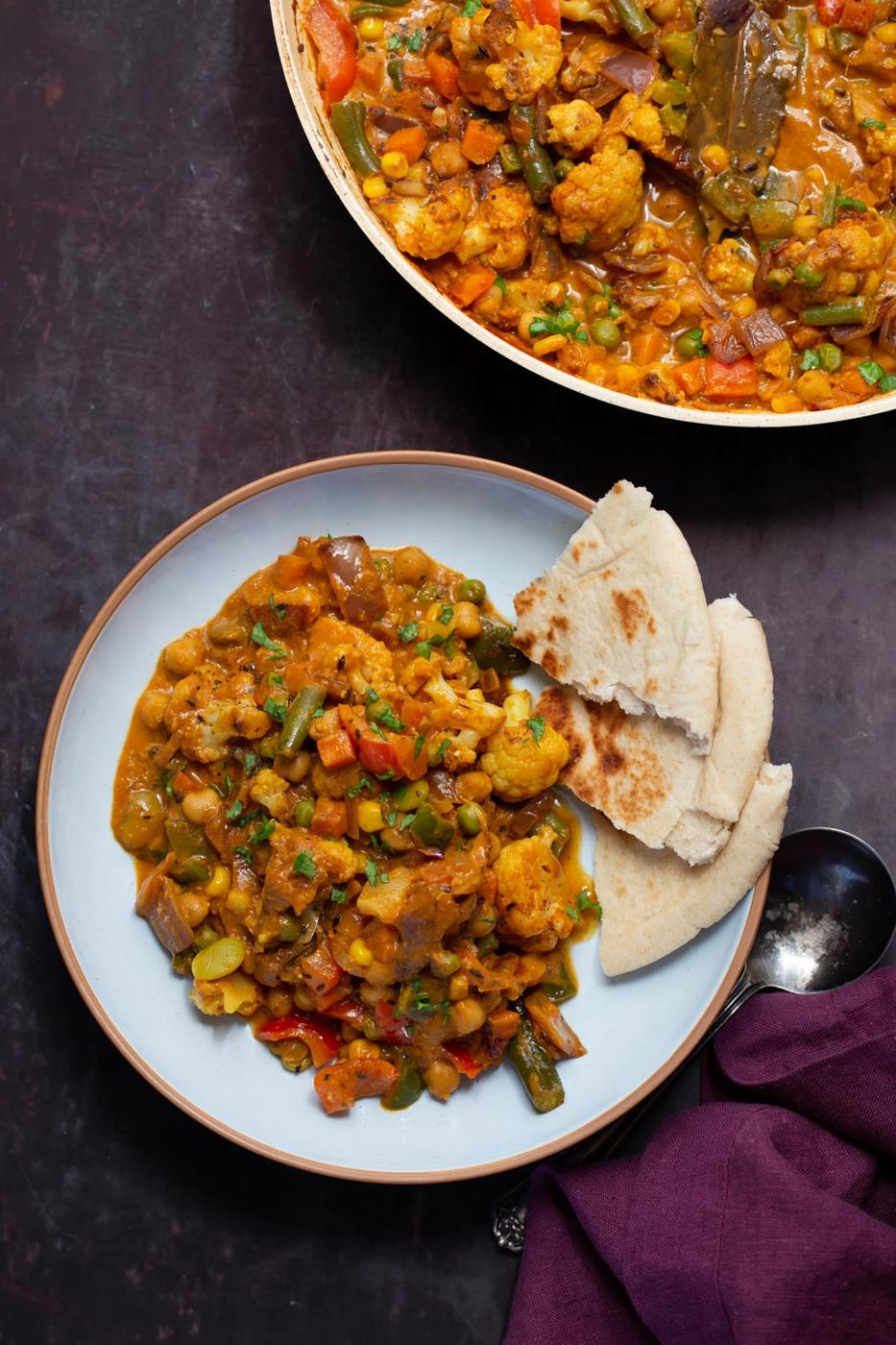 plate of vegetable bhuna next tot he pan, naan on the side for dipping