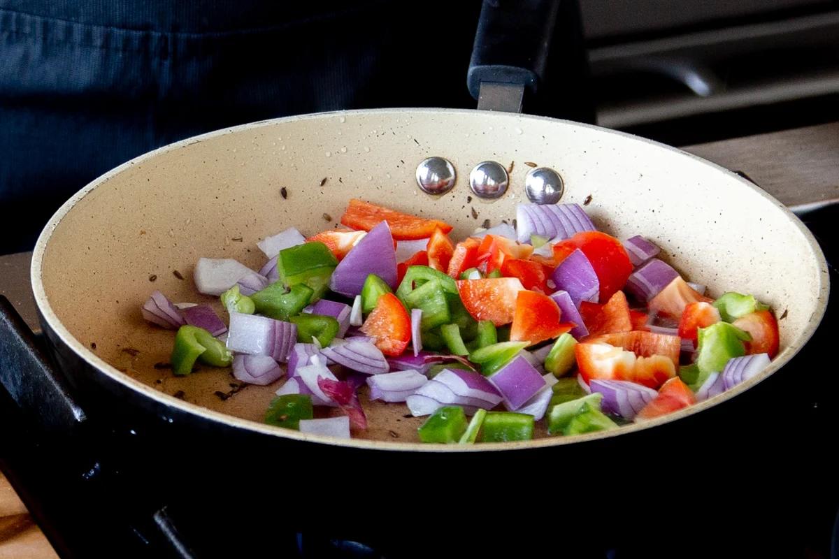 adding bell pepper and onion to the pan