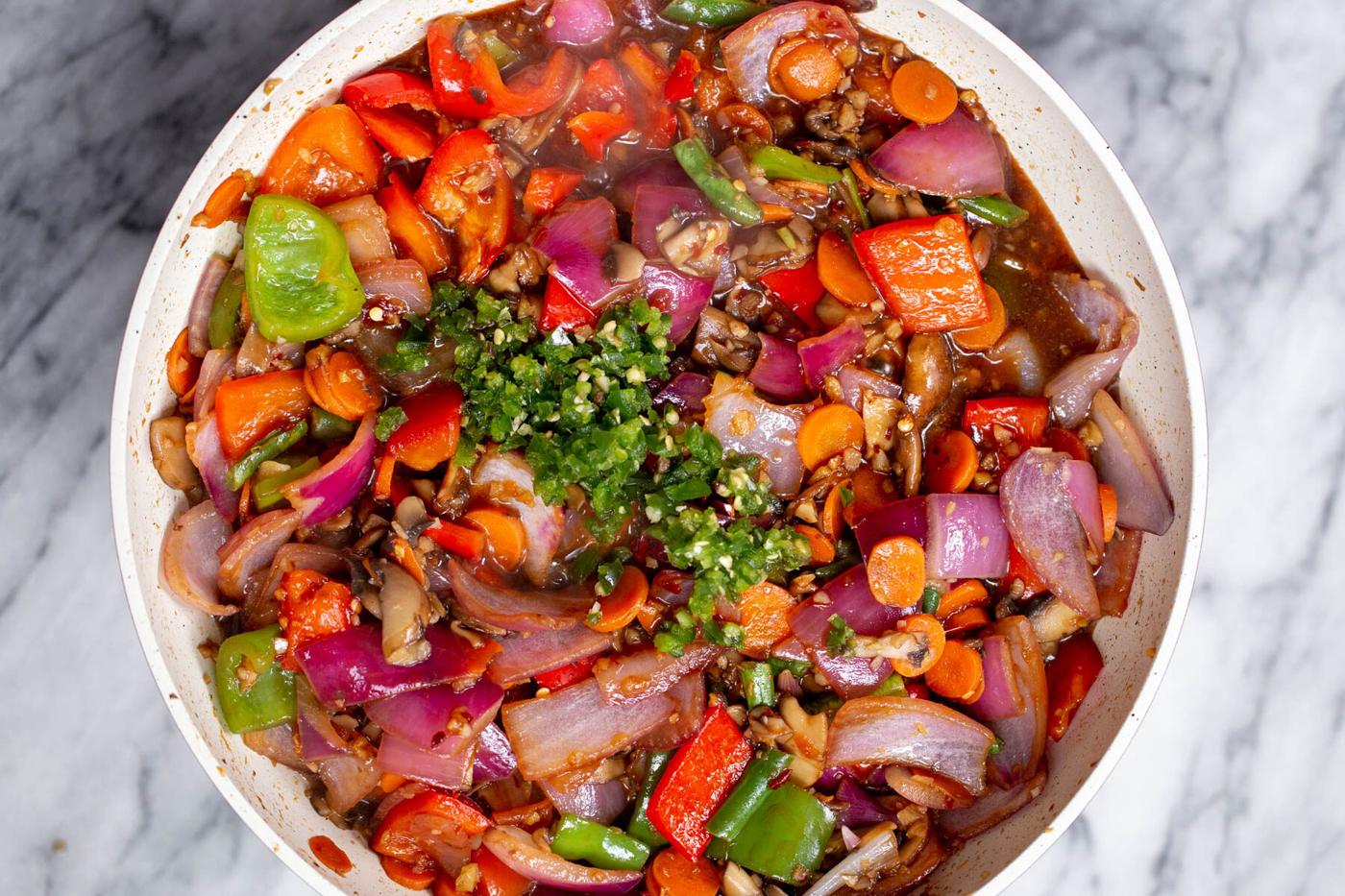 minced green chili being added to a pan with chopped veggies