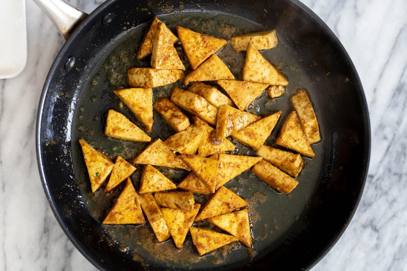 pan-fried curried tofu in a black skillet