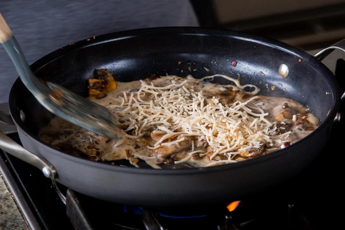 adding vegan parmesan shreds to the cooked mushrooms