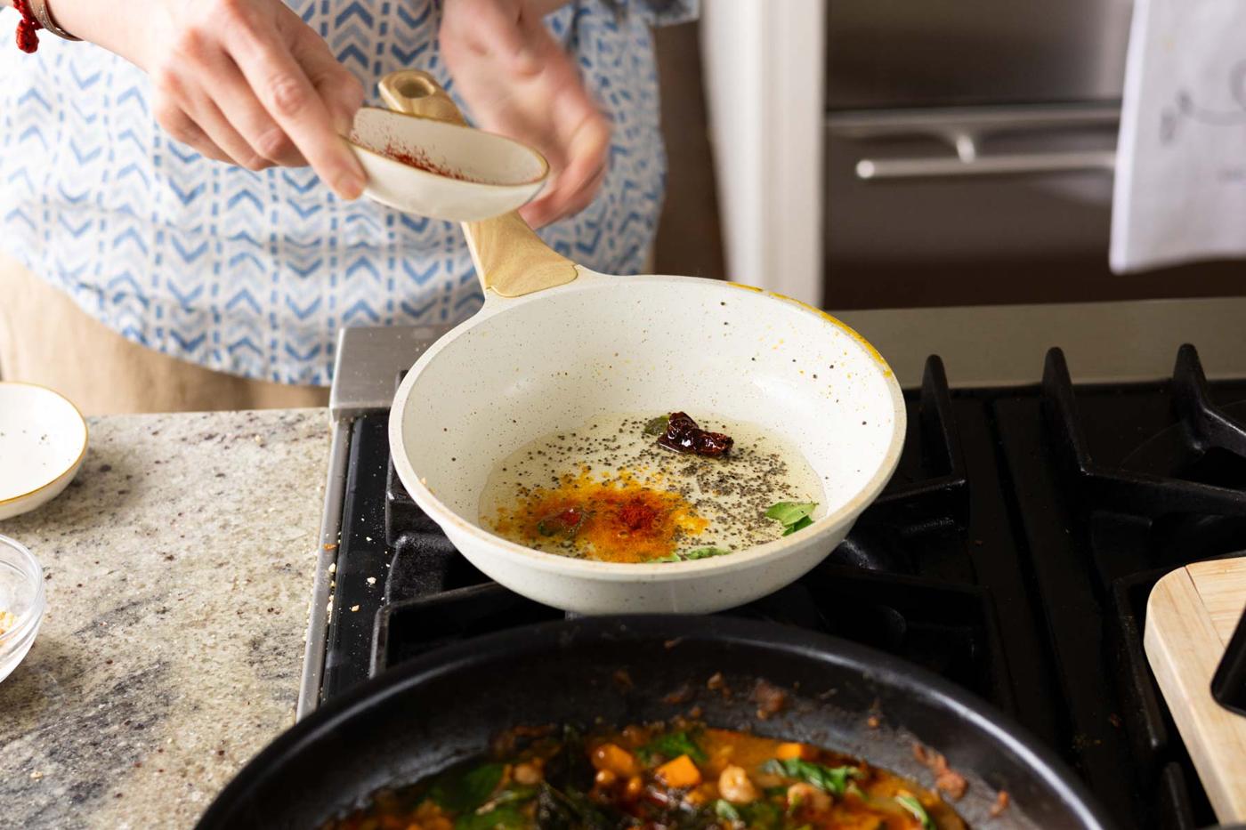 adding kashmiri chili powder to the pan of spiced oil