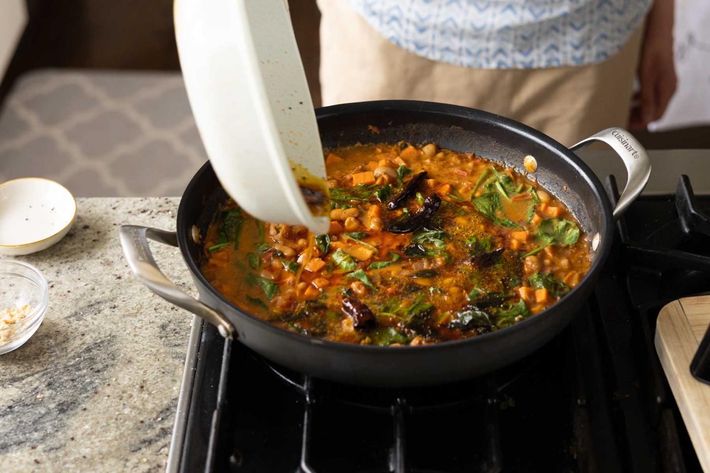 adding spiced oil to the Indian-inspired white bean stew