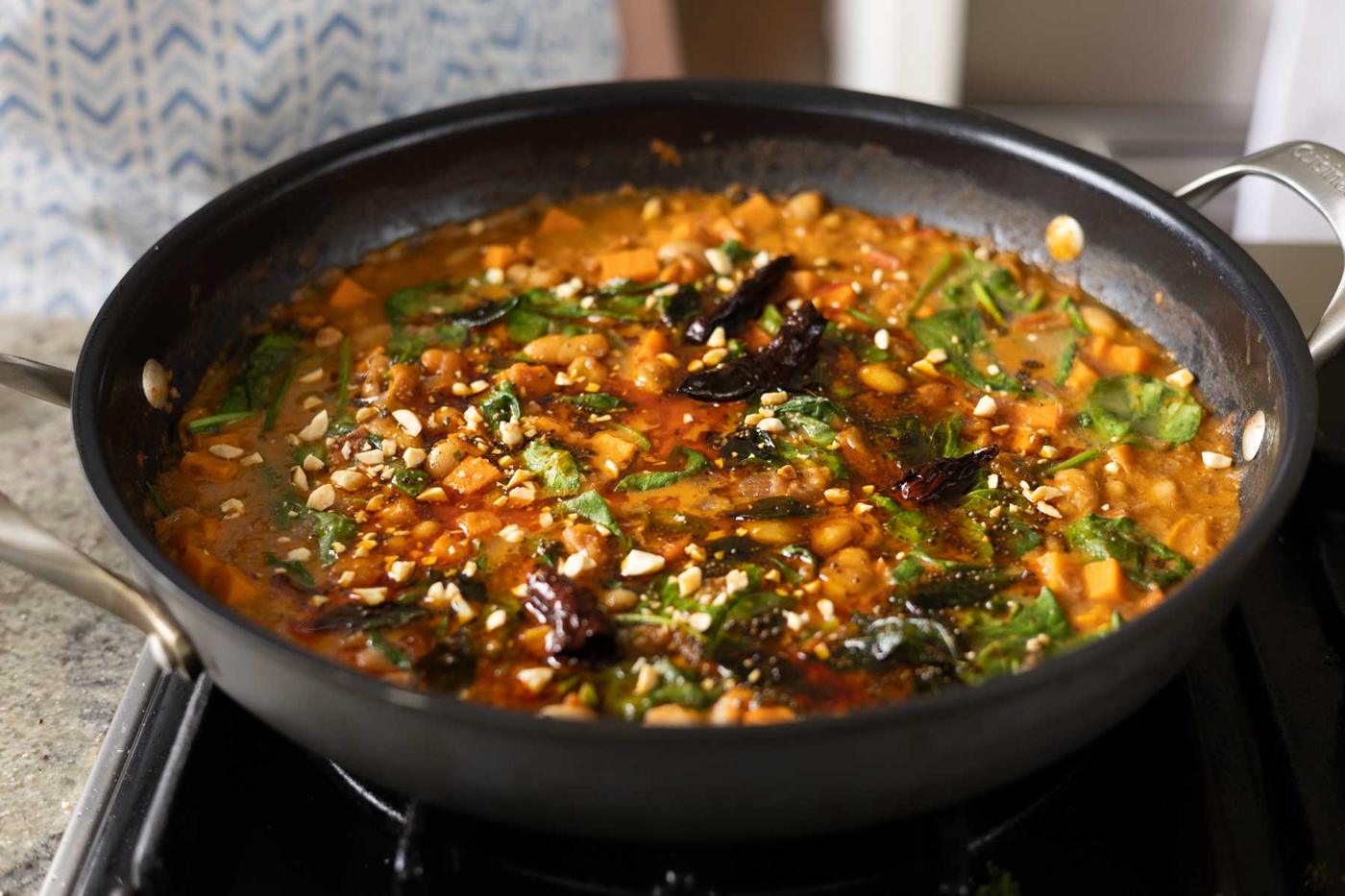 Indian-inspired white bean stew in the pan with peanuts on top