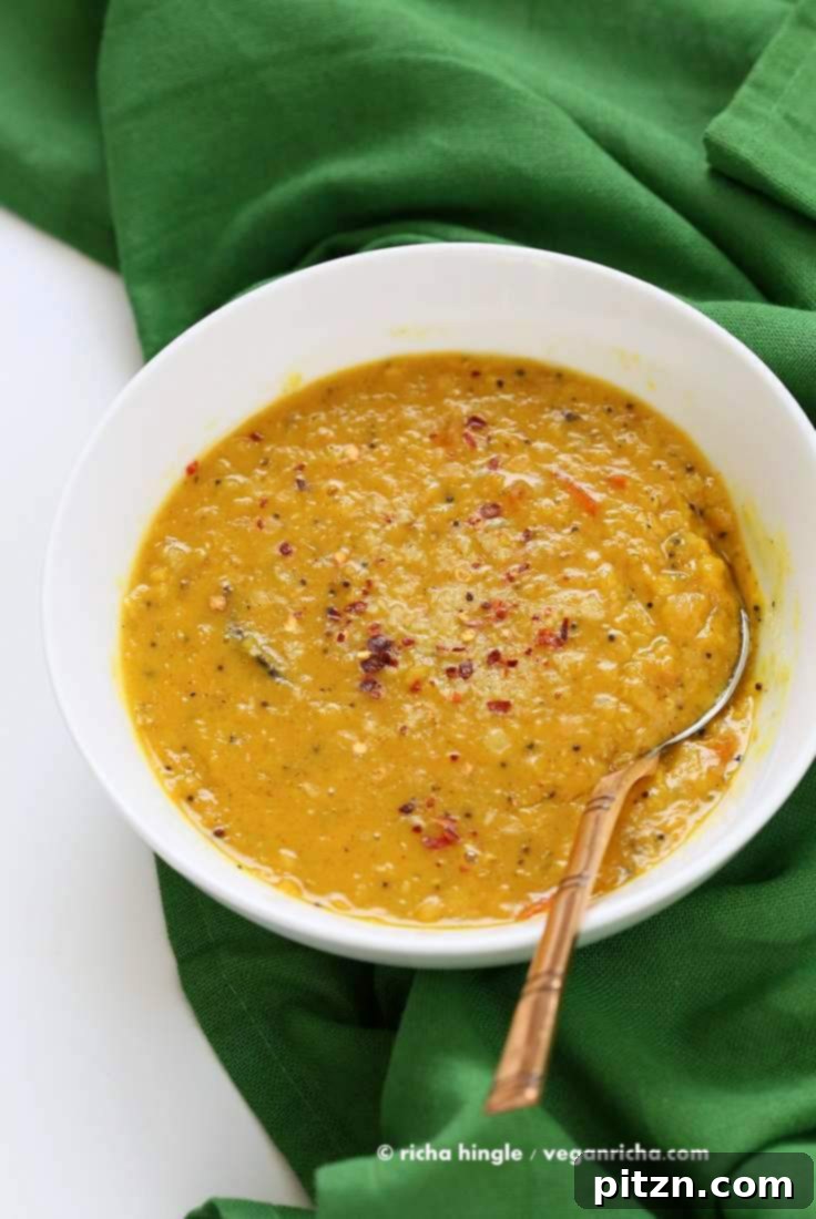 Serving of Sri Lankan Red Lentil Curry in a bowl, garnished with fresh cilantro. Easy Vegan Gluten-free Soy-free Recipe with fenugreek, cinnamon, black peppercorns, and coconut milk. No garlic recipe. | VeganRicha.com #vegan #easy #glutenfree #soyfree #lentils #dal #recipe
