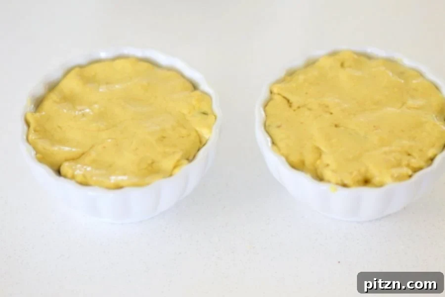 Chilled Vegan Cheese Ball mixture being removed from greased bowls, ready for shaping. Demonstrates the firm, yet pliable texture achieved with chickpea flour for a nut-free, dairy-free cheddar.