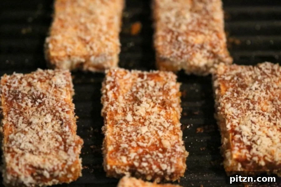 Tofu strips being coated in a seasoned breading mixture before being grilled or baked.