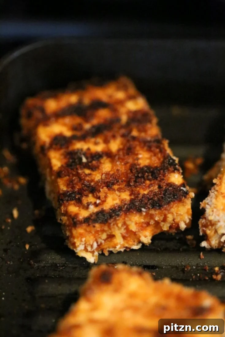 Crispy breaded tofu strips grilling on a pan, showing the golden brown crust developing.