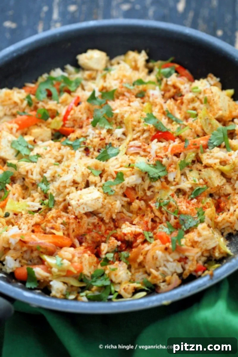 Savory Peanut Fried Rice 4 Overhead view of a wok filled with Vegan Peanut Sauce Fried Rice, tofu, carrots, red bell pepper, and cabbage, garnished with cilantro.