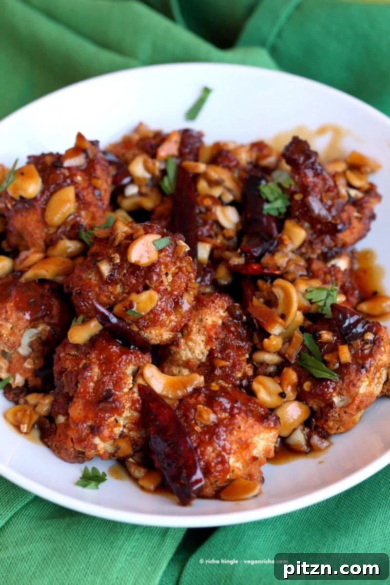 Platter of Crispy Kung Pao Cauliflower, artfully arranged with garnishes, showcasing its visual appeal as a gourmet vegan appetizer. | VeganRicha.com #vegan #appetizer #snack #cauliflower #kungpao #recipe