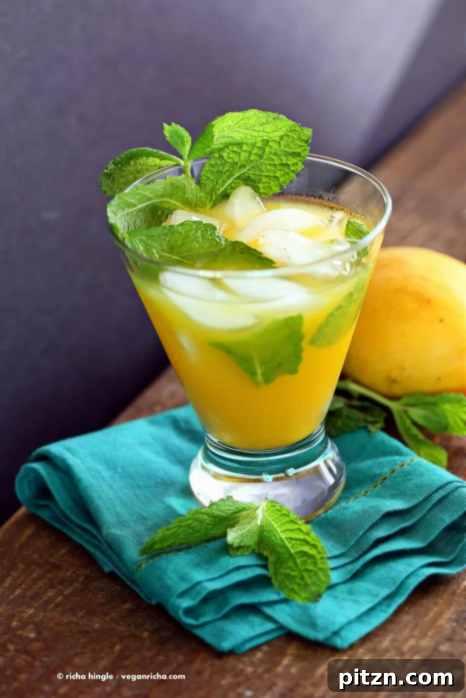 A vibrant mango mojito in a glass, garnished with fresh mint and a lime wedge. This easy-to-make, refreshing summer drink is vegan-friendly and perfect for any outdoor celebration.