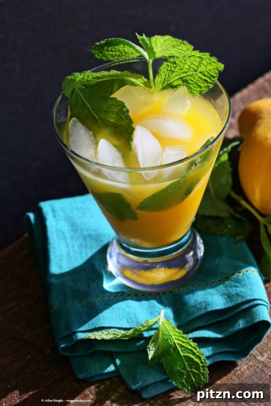Two glasses of vibrant mango mojito, garnished with fresh mint, lime, and a slice of mango, served on a light background. This sweet and tangy drink is perfect for summer.