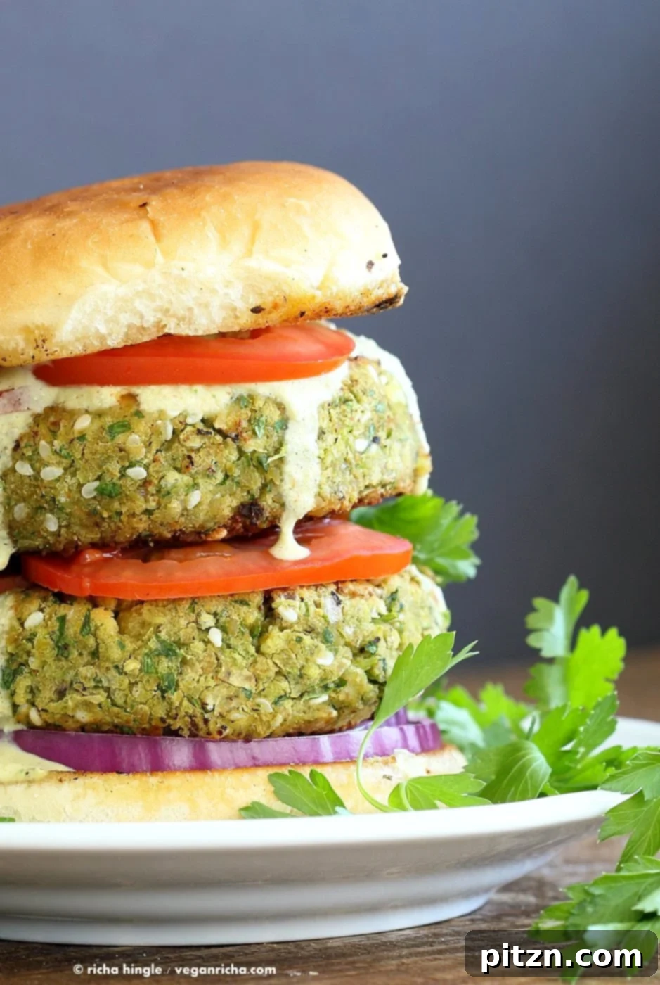 Flavorful Vegan Falafel Burgers Made Easy 6 A close-up shot of a fully assembled Easy Vegan Falafel Burger, showcasing the fluffy patty, fresh greens, and creamy dressing.