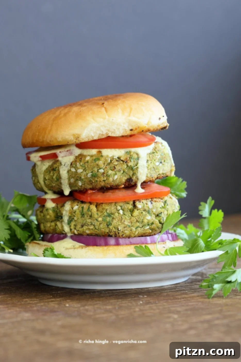 Flavorful Vegan Falafel Burgers Made Easy 7 A top-down view of several Easy Vegan Falafel Burgers, featuring the golden patties, crisp vegetables, and a generous drizzle of tahini sauce, ready to be enjoyed.