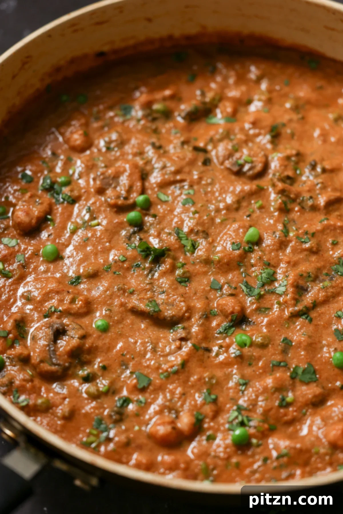 Close-up of a vibrant bowl of Mushroom Matar Masala, showcasing the creamy tomato sauce, tender mushrooms, and bright green peas, garnished with fresh cilantro.