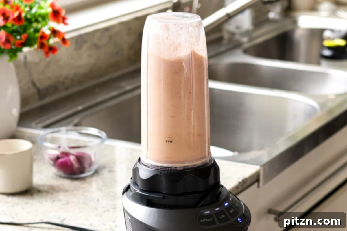 The blender actively processing the tomato and cashew mixture, creating a smooth, creamy sauce for the Matar Masala.
