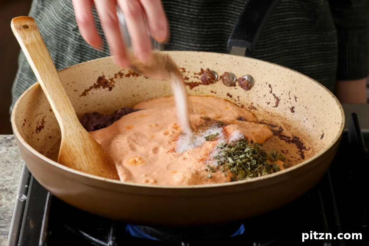 Adding salt, sugar, and additional spices to the simmering tomato masala sauce in the pan, enhancing the flavor profile.