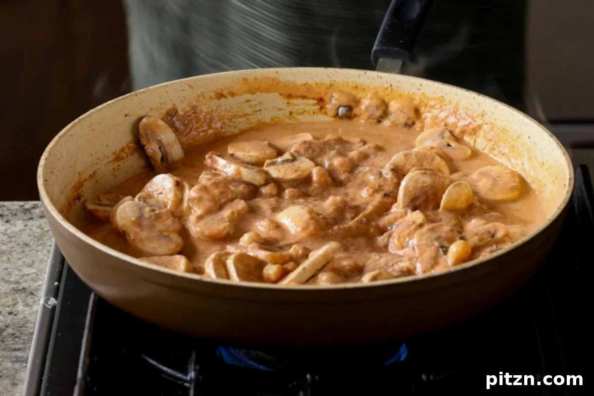Mushrooms and chickpeas thoroughly mixed into the fragrant matar masala sauce, ready to simmer and absorb flavors.