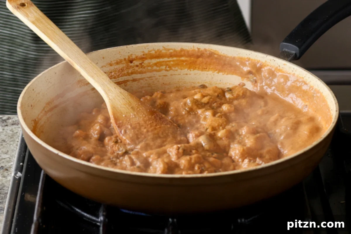 Mushroom Matar Masala simmering in the pan after the mushrooms have cooked down, showing a rich, thick sauce.