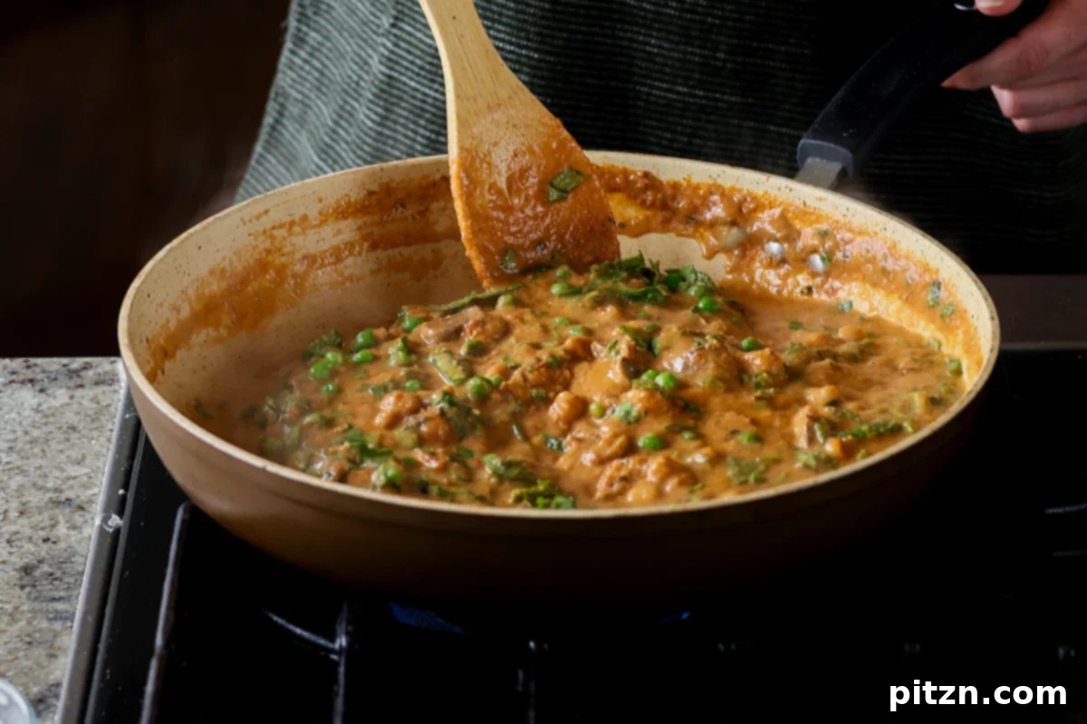 Fresh peas being gently stirred into the rich and creamy matar masala sauce, adding a burst of color and sweetness.