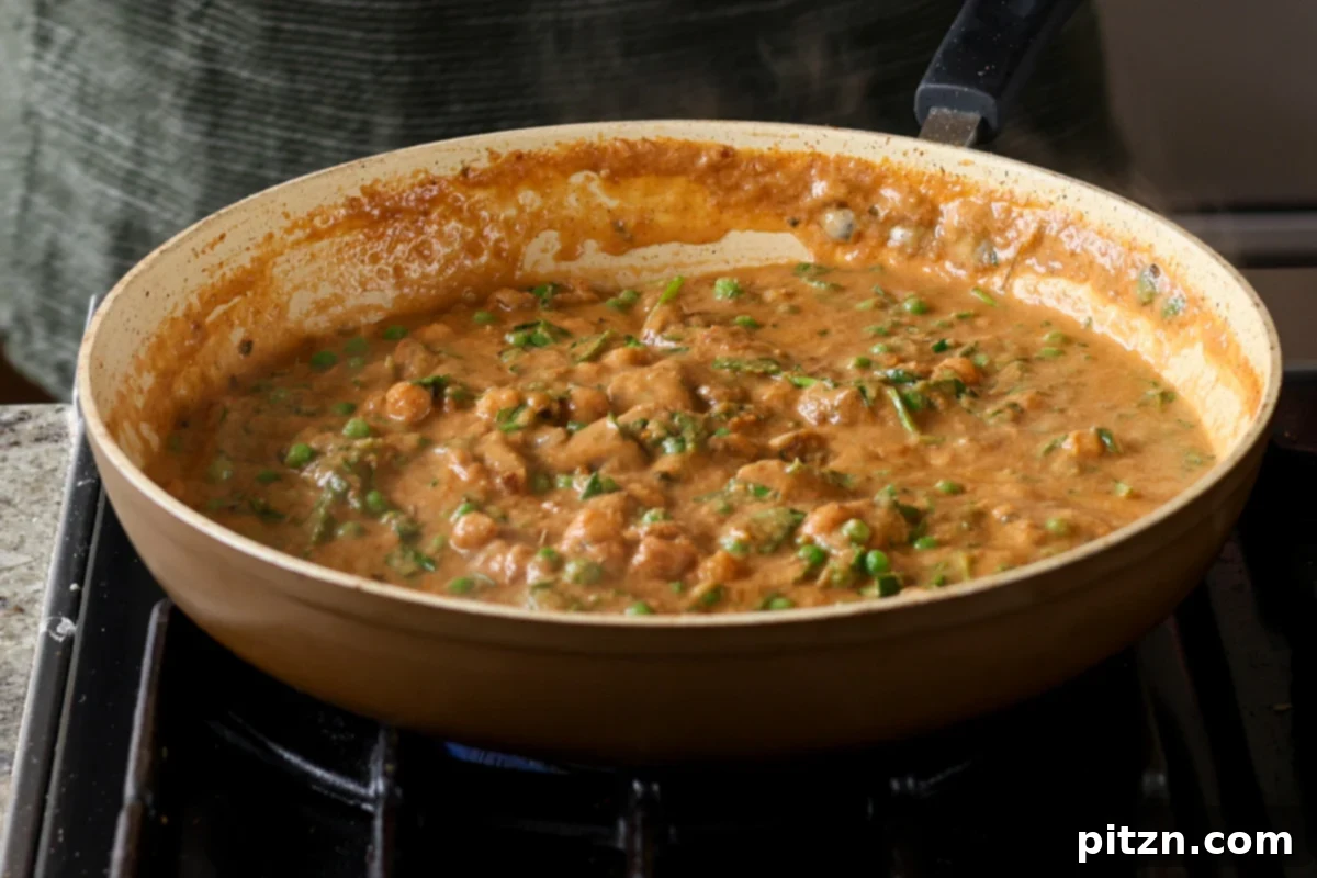 The finished Mushroom Matar Masala in the pan, glistening with rich sauce and ready to be served, garnished with fresh herbs.