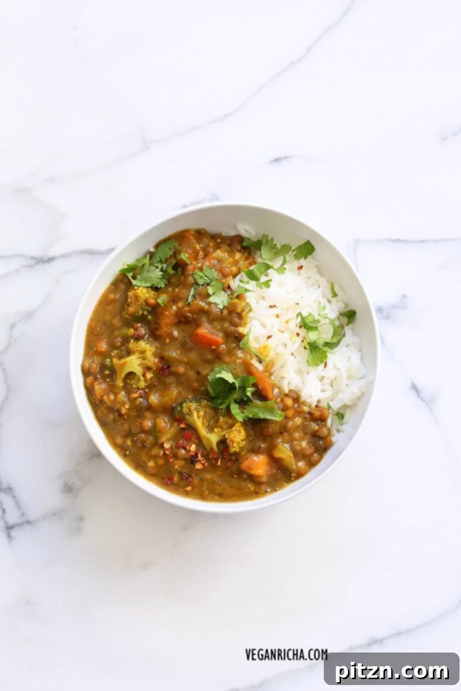 A bowl of delicious Brown Lentil Soup with Broccoli, Fenugreek, Turmeric, and Black Pepper, garnished with fresh herbs. A warming and healthy vegan dal.