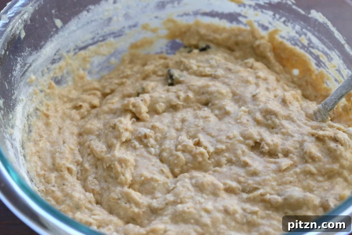 Pouring vegan banana bread batter into a parchment-lined loaf pan. 