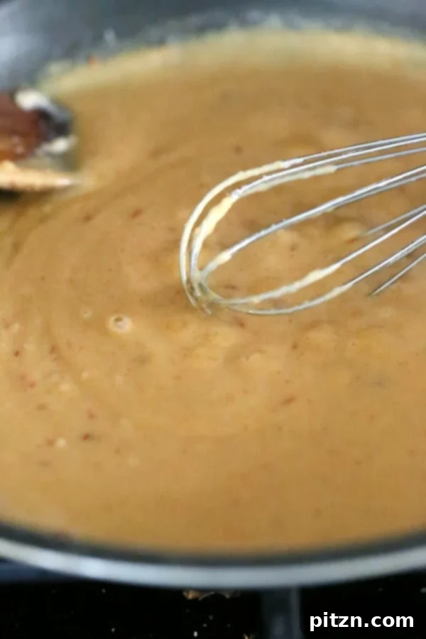 vegan mac and cheese sauce being stirred with a metal whisk in a saucepan