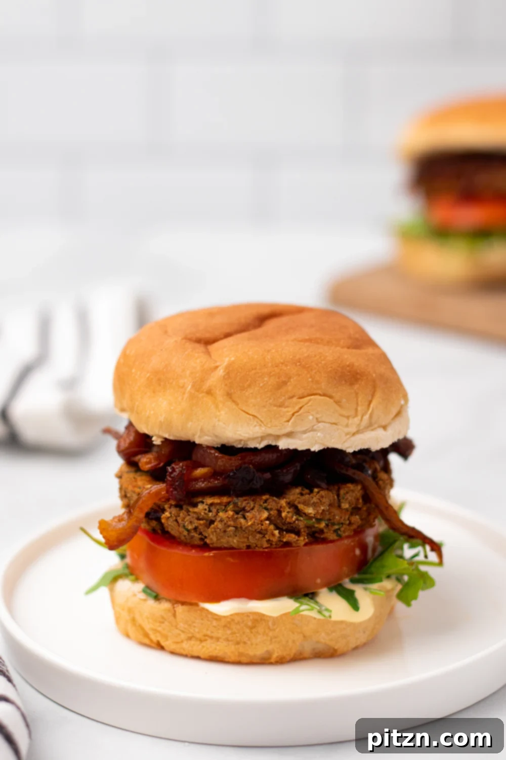 chickpea burger side view of a Middle Eastern Za'atar spiced chickpea burger with caramelized onion and hummus on a white plate