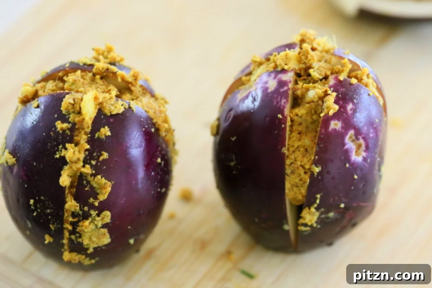 Carefully stuffing baby eggplants with the aromatic masala paste, ready for cooking.