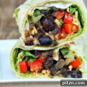 a healthy vegan wrap cut in half revealing a black bean and spinach filling