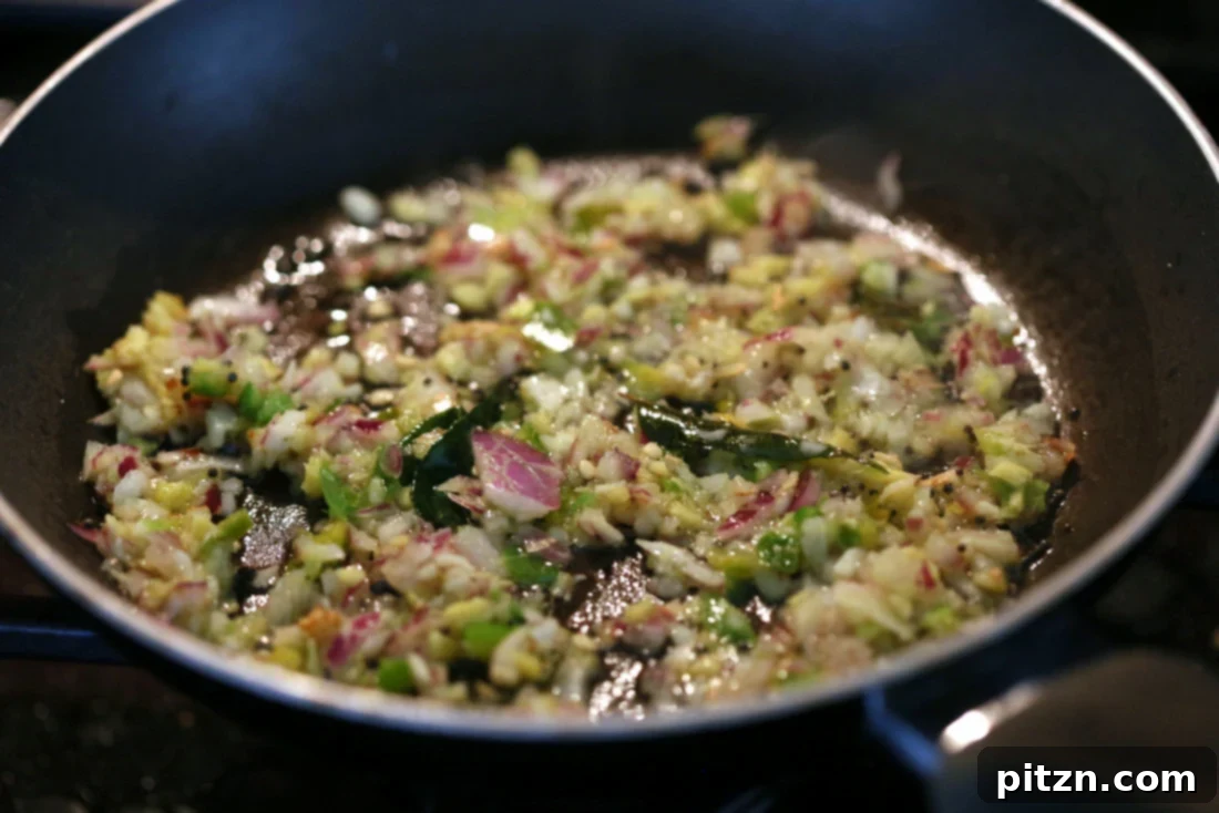 Spiced Smashed Potatoes with a Mustard Ginger Infusion 7 A small skillet on the stovetop, containing the aromatic mustard-ginger tempering with spices, garlic, ginger, and green chilies sizzling in oil.