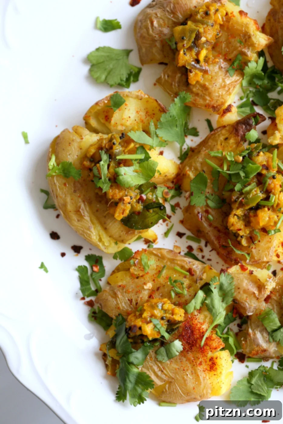 Spiced Smashed Potatoes with a Mustard Ginger Infusion 9 Platter of Indian Spiced Smashed Potatoes with Mustard Ginger Tempering, garnished with lemon wedges and fresh cilantro, presented beautifully for serving.