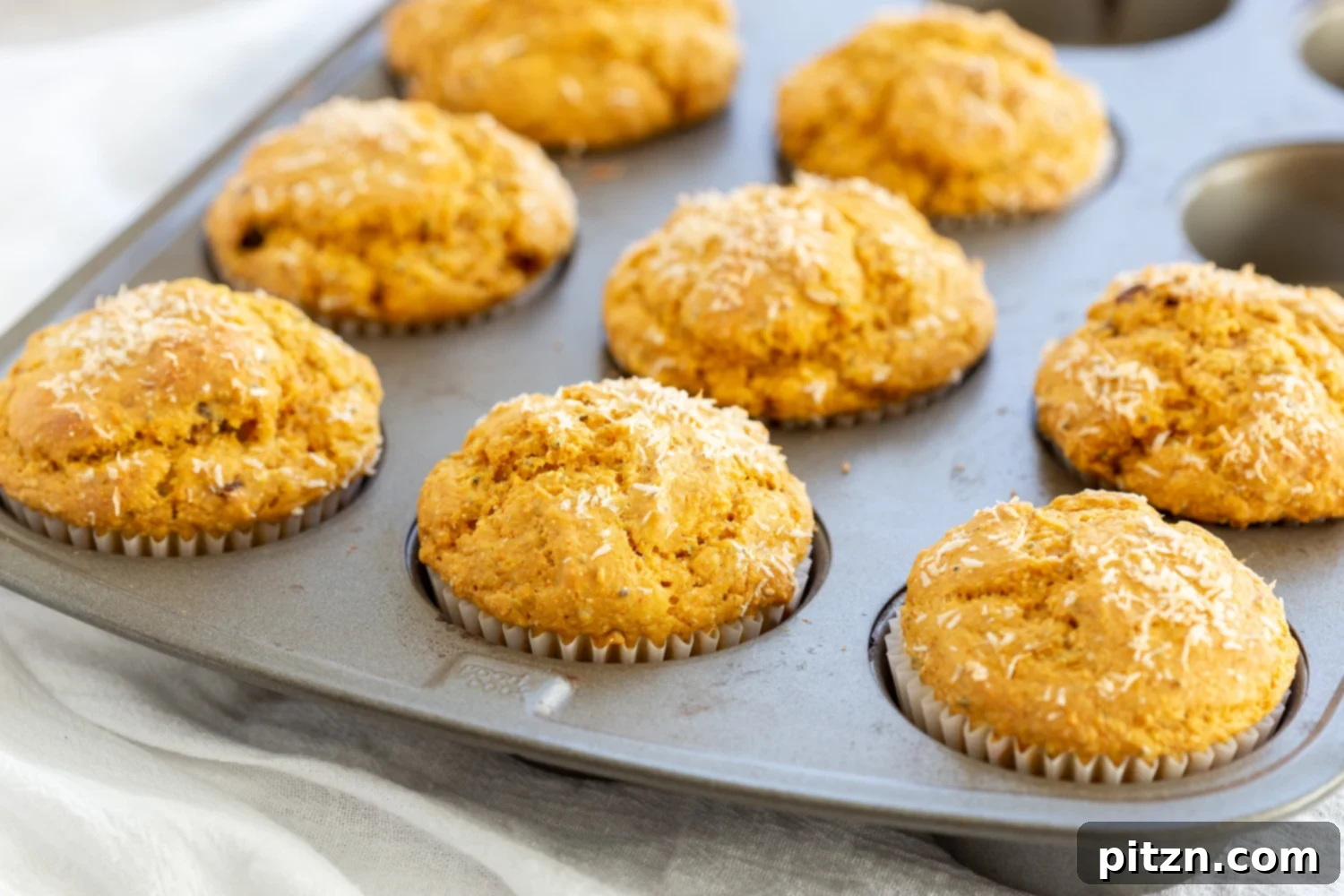 Soft, gorgeous Vegan Turmeric Carrot Muffins cooling in a muffin pan after baking